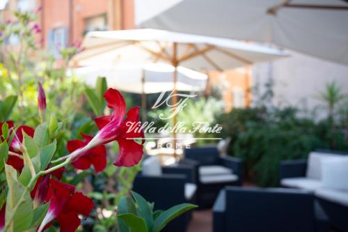 a red flower in front of a table and an umbrella at Villa della Fonte in Rome
