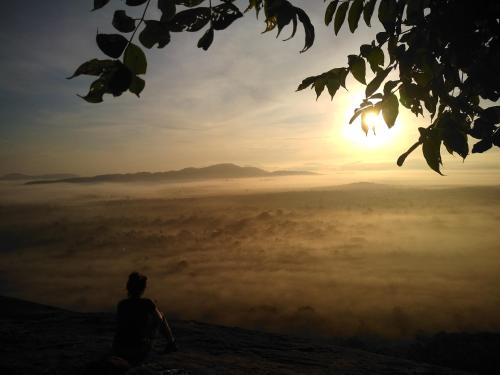 a person sitting on top of a mountain watching the sunset at Grand freedom in Sigiriya