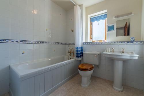 uma casa de banho com um WC, uma banheira e um lavatório. em Keepers Cottage em Wadebridge