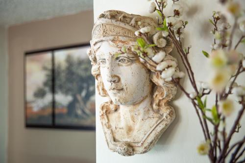 a bust of a woman on a wall with flowers at Victoria Hill Hotel in Dassia