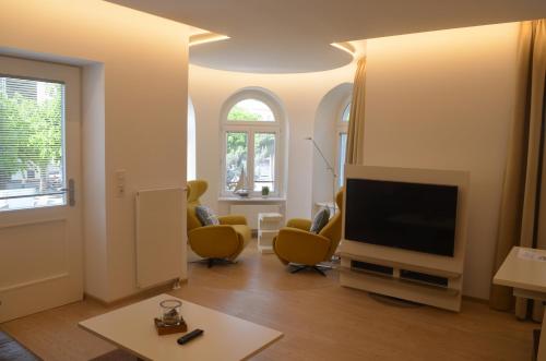 uma sala de estar com uma televisão de ecrã plano e cadeiras amarelas em "Strandläufer" Villa Odin em Ostseebad Sellin
