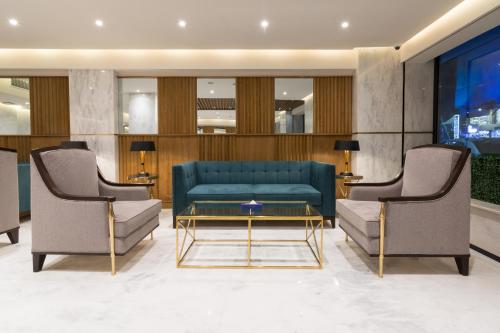 a lobby with a couch and two chairs and a table at Hotel Excelsior Karachi in Karachi