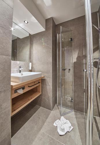 a bathroom with a sink and a shower at Hotel Hubertushof in Saalbach Hinterglemm