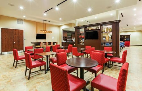 a dining room with tables and red chairs at Clarion Hotel The Colony - Plano West in The Colony