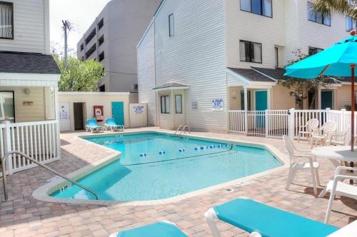 a swimming pool with chairs and a table and an umbrella at Ocean Dunes Villa I 5110 & 5111 in Myrtle Beach