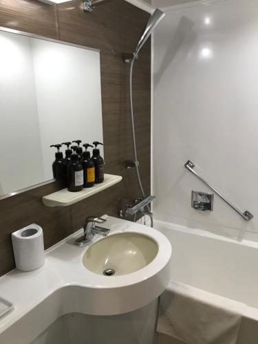 a white bathroom with a sink and a shower at Hotel Avan Sukumo in Sukumo