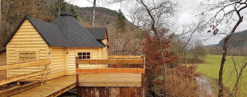 a log cabin with a wooden deck and a black roof at NatureZenKota in Mittlach