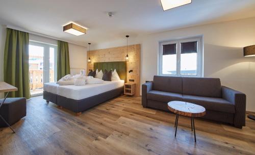 a hotel room with a bed and a couch at Hotel Hubertushof in Saalbach Hinterglemm