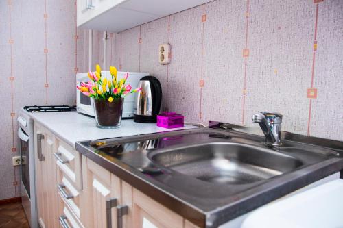 a kitchen counter with a sink and flowers in a vase at 1 комнатная квартира, in Kokshetau
