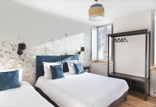 two beds in a hotel room with a window at Hôtel Tourmalet in Luz-Saint-Sauveur