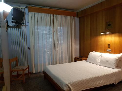 a bedroom with a bed and a chair and a television at Hotel Nordeste Shalom in Bragança