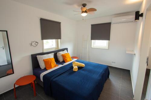 ein Schlafzimmer mit einem blauen Bett und orangefarbenen Kissen in der Unterkunft Kas Honkie Tonkie in Kralendijk