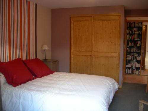 - une chambre avec un grand lit blanc et des oreillers rouges dans l'établissement Gîte La Penhatière, à Baulon
