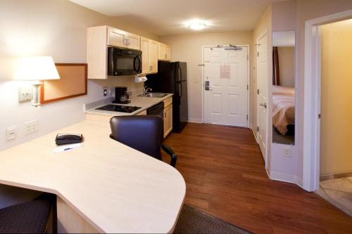 a small kitchen with a table and a room with a bed at Candlewood Suites Minot by IHG in Minot