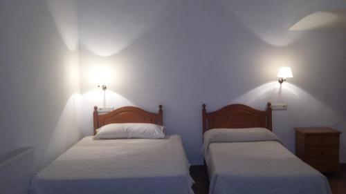Habitacion de la marquesa في Alcoleja: سريرين في غرفة مع مصباحين على الحائط