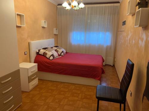 1 dormitorio con 1 cama con manta roja y ventana en Apartamento Naron, en Narón
