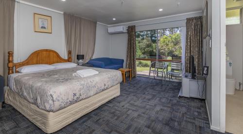 a bedroom with a bed and a sliding glass door at Riverside Lodge Paihia in Paihia
