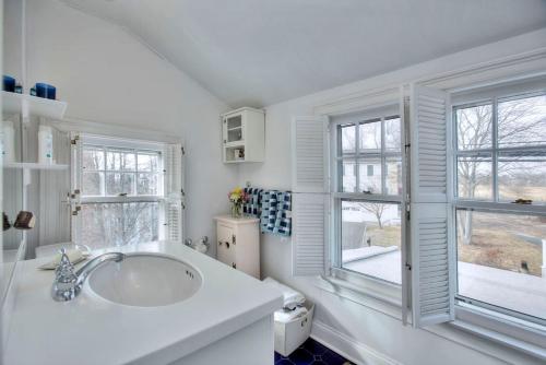 baño blanco con lavabo y 2 ventanas en Gem by the Sound - Beach Front, en Fairfield