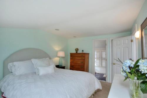 Un dormitorio con una cama blanca y un jarrón de flores en Gem by the Sound - Beach Front, en Fairfield