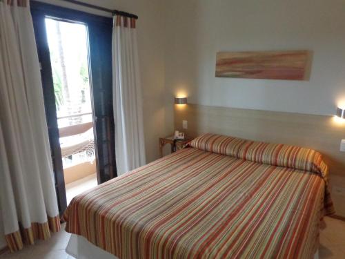 a bedroom with a bed and a large window at Hotel Costa Balena-Piscina Aquecida Coberta in Guarujá