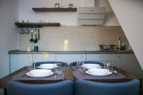 una mesa con sillas, platos y copas de vino en Lukas Superior Apartment & SPA, en Zlatibor