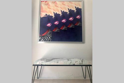 a painting hanging on a wall next to a bench at CARMELORIA III in Rincon