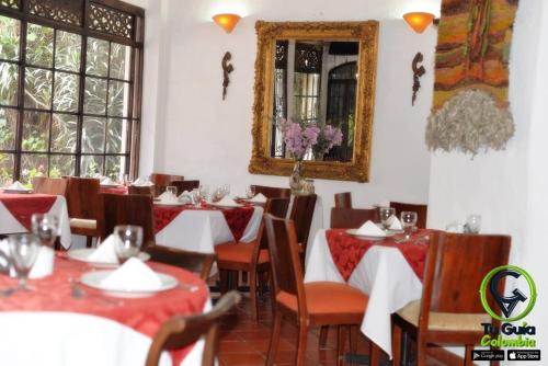 un restaurante con mesas, sillas y espejo en Hotel Los Frayles, en Villa de Leyva