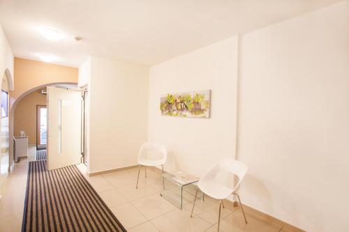 a hallway with white chairs and a table and a painting at Hotel U Tří hrušek suites & apartments in České Budějovice