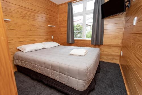 a small bedroom with a bed and a window at Wellington TOP 10 Holiday Park in Lower Hutt
