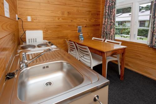 uma cozinha com um lavatório de aço inoxidável e uma mesa em Wellington TOP 10 Holiday Park em Lower Hutt