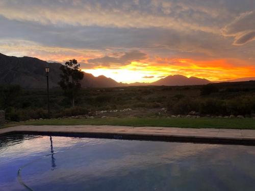 a sunset over a swimming pool with the mountains in the background at 360on62 Farm Cottages in Montagu