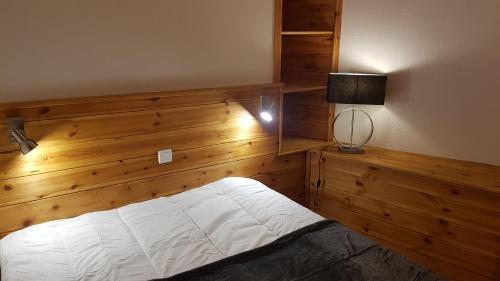 een slaapkamer met een bed met een houten muur bij Très bel appartement pied de pistes 6 pers Serre Chevalier Chantemerle in Saint-Chaffrey