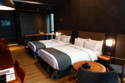 Habitación de hotel con 2 camas, mesa y sillas en Khokak Panoramas Hotel, en Gukeng