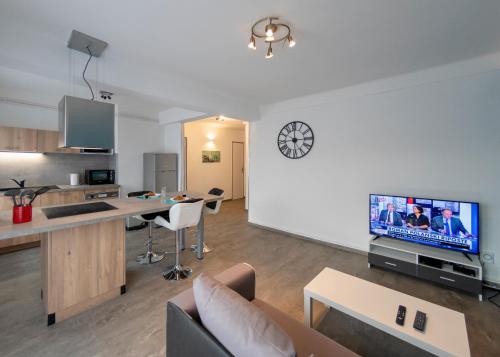 ein Wohnzimmer mit einem Sofa und eine Küche mit einem TV in der Unterkunft Appart'Hôtel de la Gare in Montbéliard