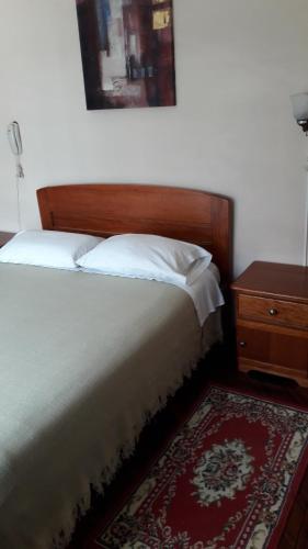 a bed with a wooden headboard next to a table at Hostal Santa María Gracia in Quito