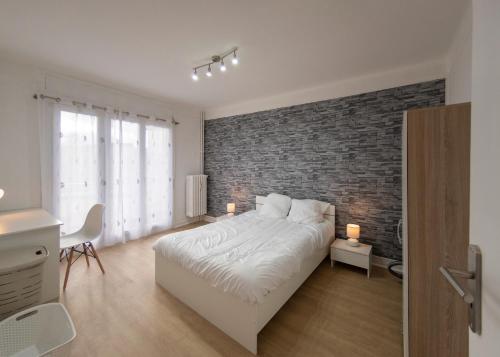 a bedroom with a white bed and a brick wall at Appart'Hôtel de la Gare in Montbéliard