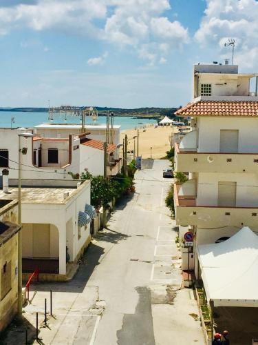 a street with buildings and a beach in the background at Relax Near The Sea in Noto Marina
