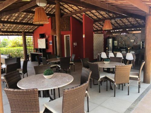 ein Restaurant mit Tischen, Stühlen und roten Wänden in der Unterkunft Itacimirim - Quinta das Lagoas Residence in Itacimirim
