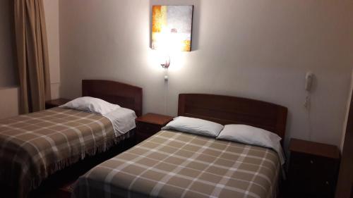 una habitación de hotel con 2 camas y una lámpara en Hostal Santa María Gracia, en Quito