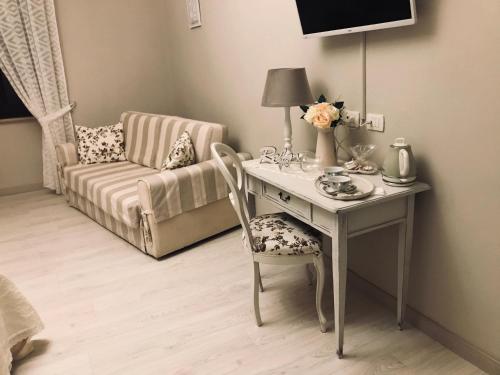 a room with a desk with a chair and a couch at Domo 'e sa rosa in Bosa