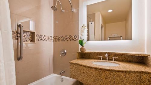 a bathroom with a sink and a mirror and a tub at Best Western Plus Ontario Airport & Convention Center in Ontario