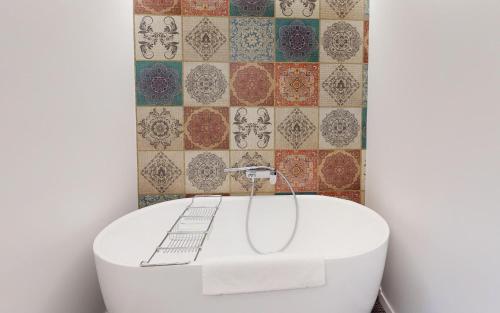 a white tub in a bathroom with a tiled wall at Au Réduit U06 in St. Moritz