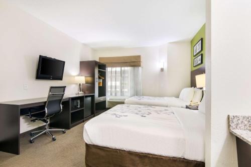 a hotel room with two beds and a desk at Sleep Inn Peachtree City - Atlanta in Peachtree City