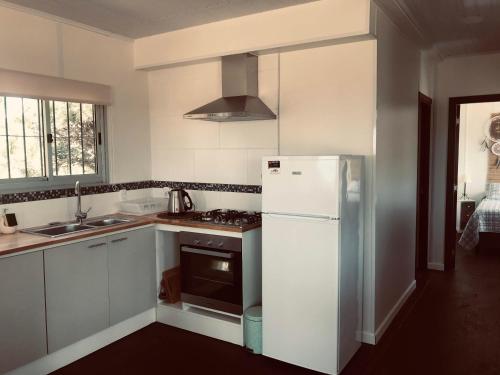cocina blanca con nevera y fregadero en La Bruna, en Balneario Buenos Aires