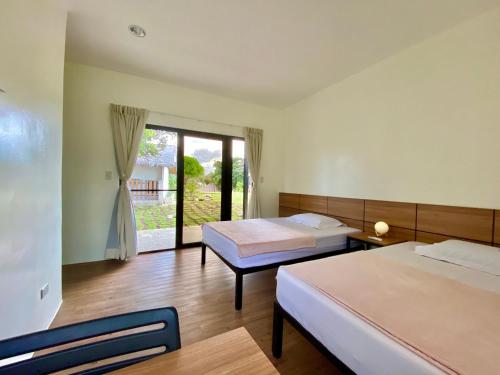 a hotel room with two beds and a window at Casa de Moalboal in Moalboal