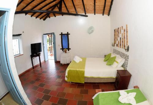 a bedroom with a bed and a tv in a room at Hotel Campestre El Santuario in Barichara