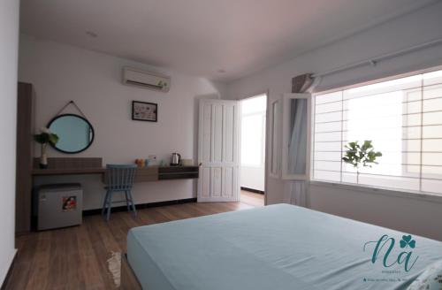 a bedroom with a bed and a desk and two windows at Na Homestay in Hue