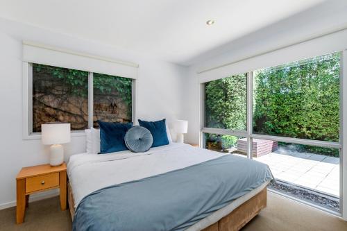 a bedroom with a large bed and large windows at The Victoria Apartments in Port Fairy