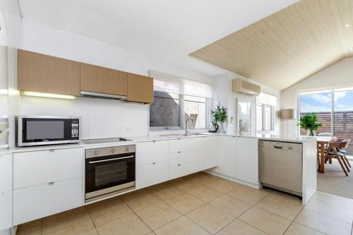 a kitchen with white cabinets and a large window at The Victoria Apartments in Port Fairy
