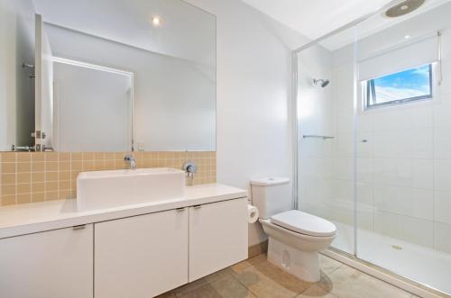 a white bathroom with a toilet and a shower at The Victoria Apartments in Port Fairy
